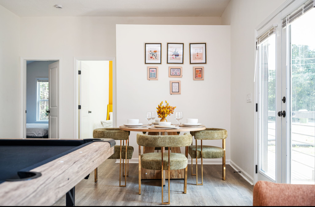 Dining and game area with round table, olive chairs, gallery wall and pool table