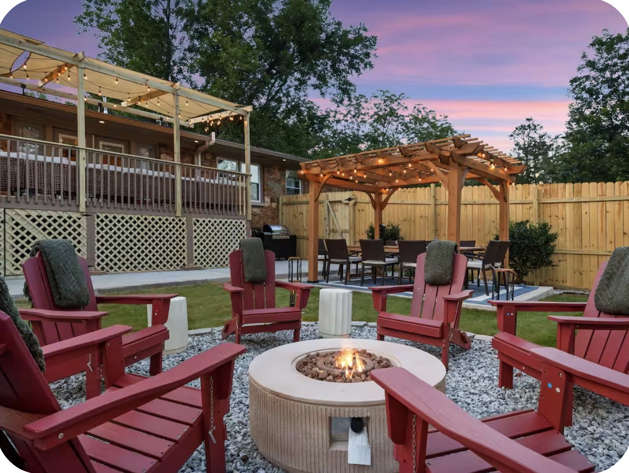 Fire-pit seating with red Adirondack chairs, pergola dining and string lights at dusk