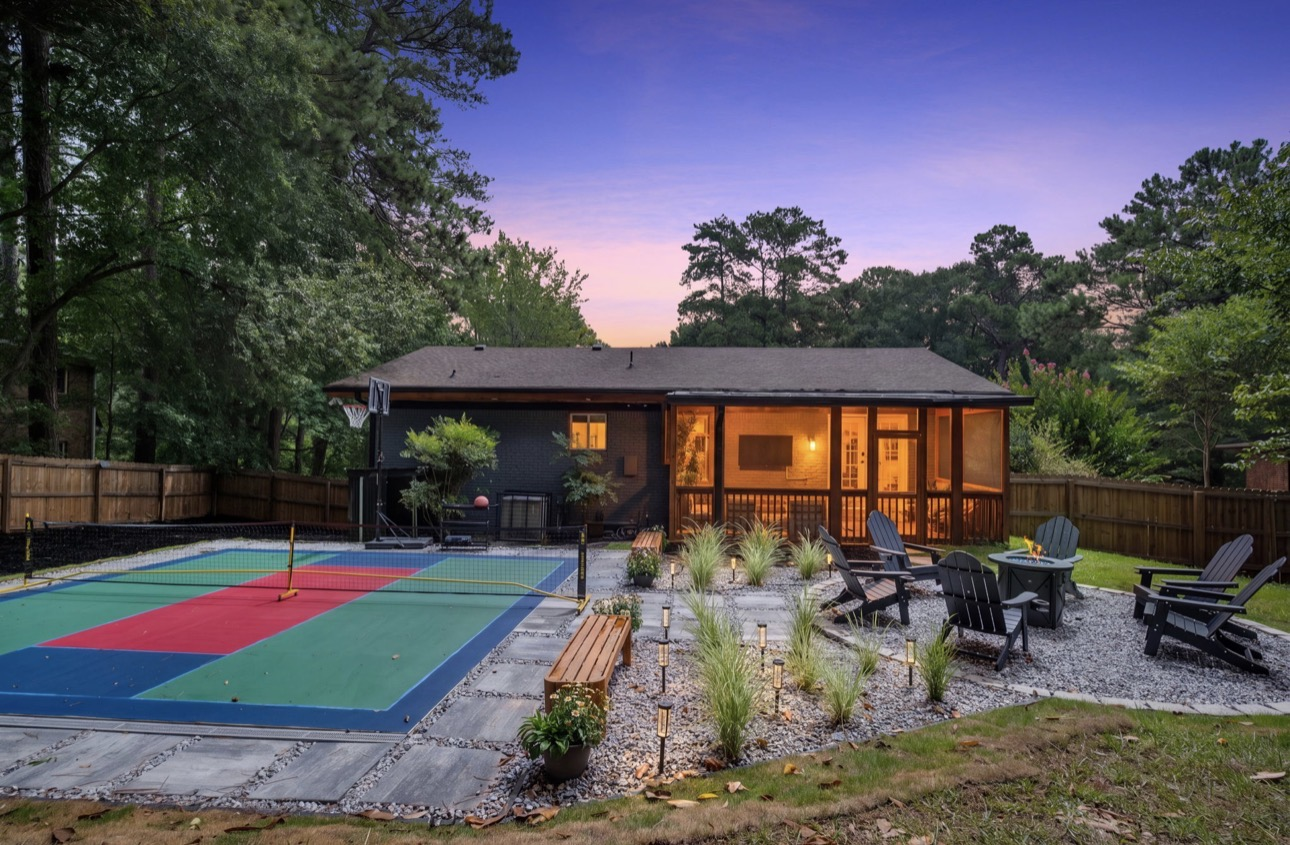 Twilight backyard with multi-sport pickleball court, fire table and Adirondack seating