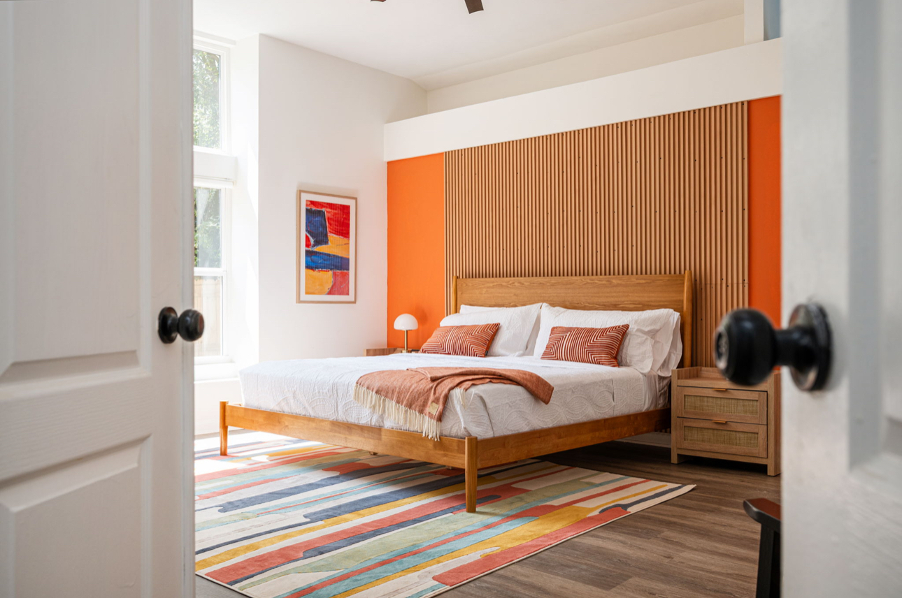 Primary bedroom with orange accent wall, wood slat feature wall and terracotta bedding