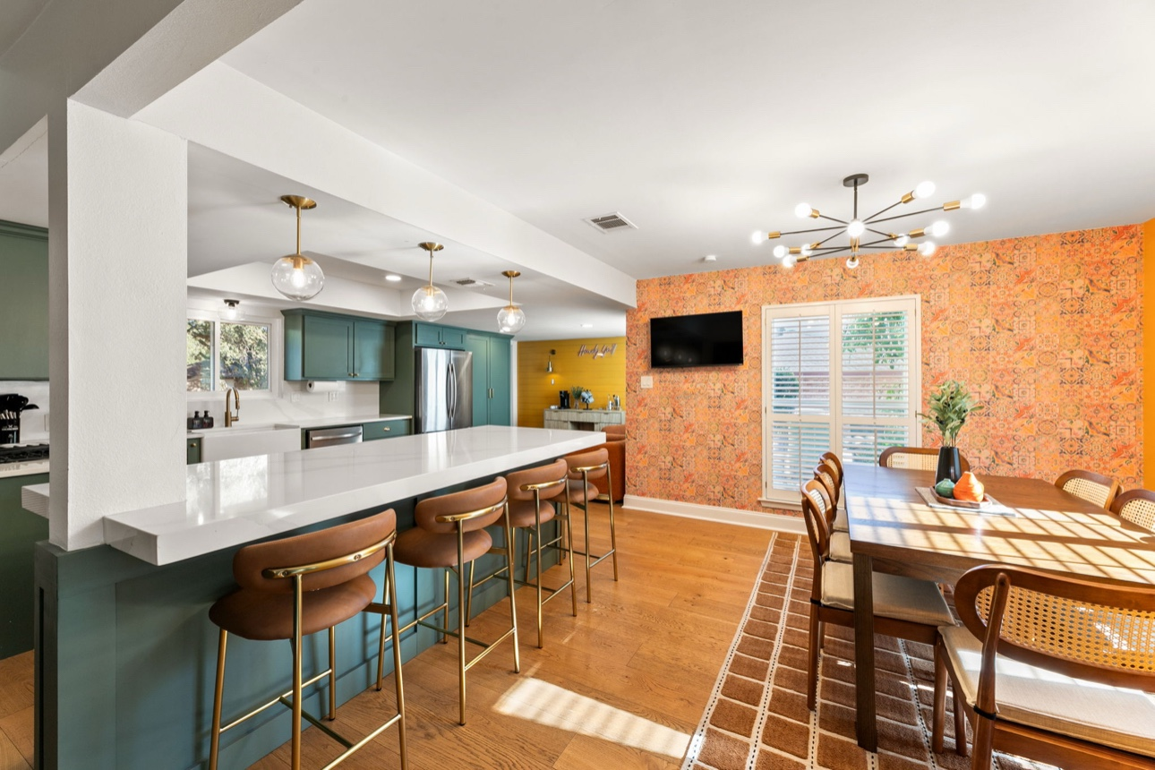 Teal cabinet kitchen with brass barstools and warm wood counter seating