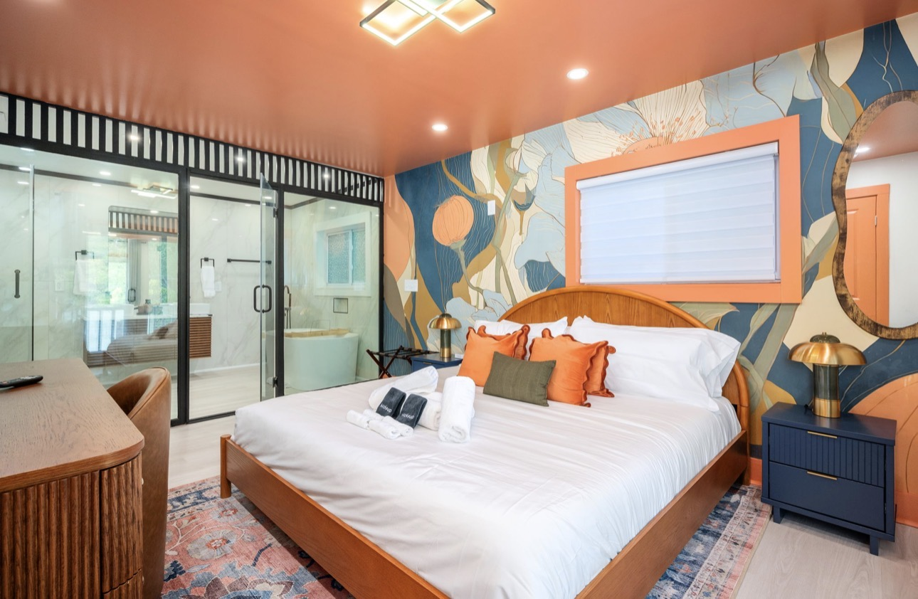 Primary bedroom with terracotta ceiling, botanical mural wall and spa bath behind glass