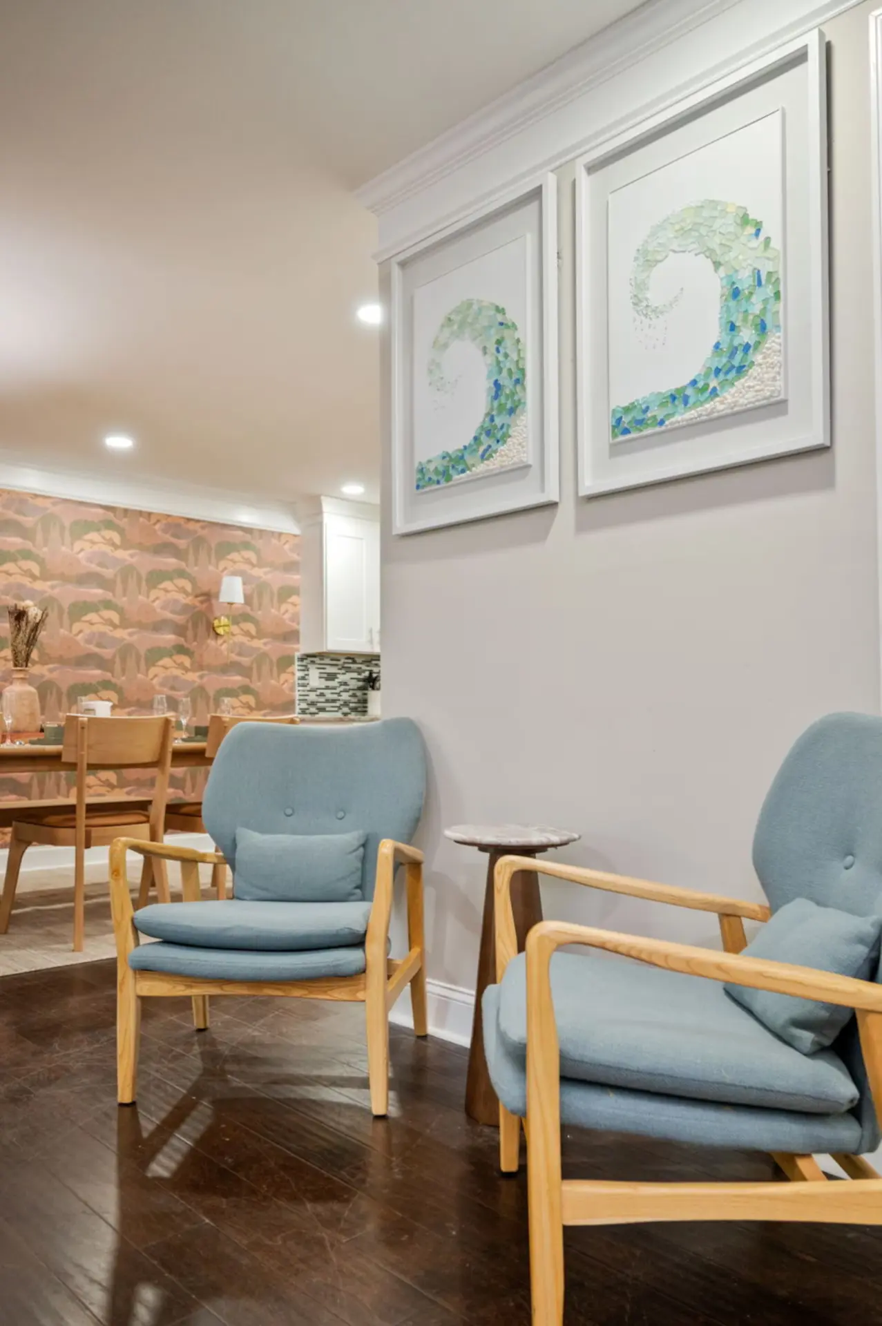 Sitting nook with blue mid-century chairs and framed sea glass wave art
