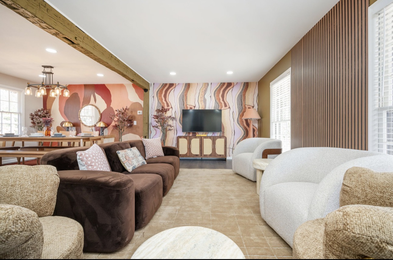 Open-concept living and dining room with mural wallpaper, slat wall, and boucle seating
