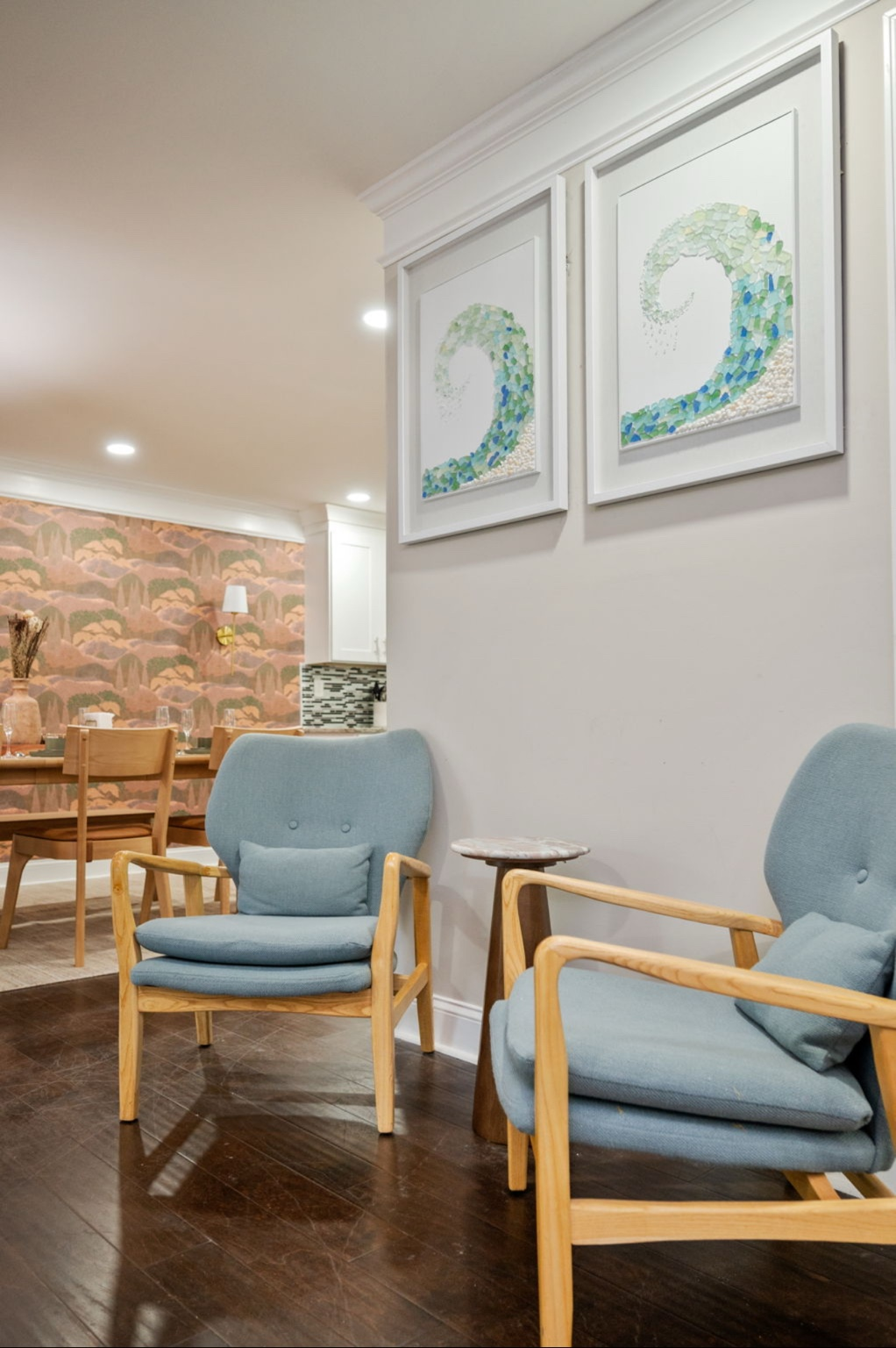 Pair of blue lounge chairs beneath framed sea-glass wave artwork