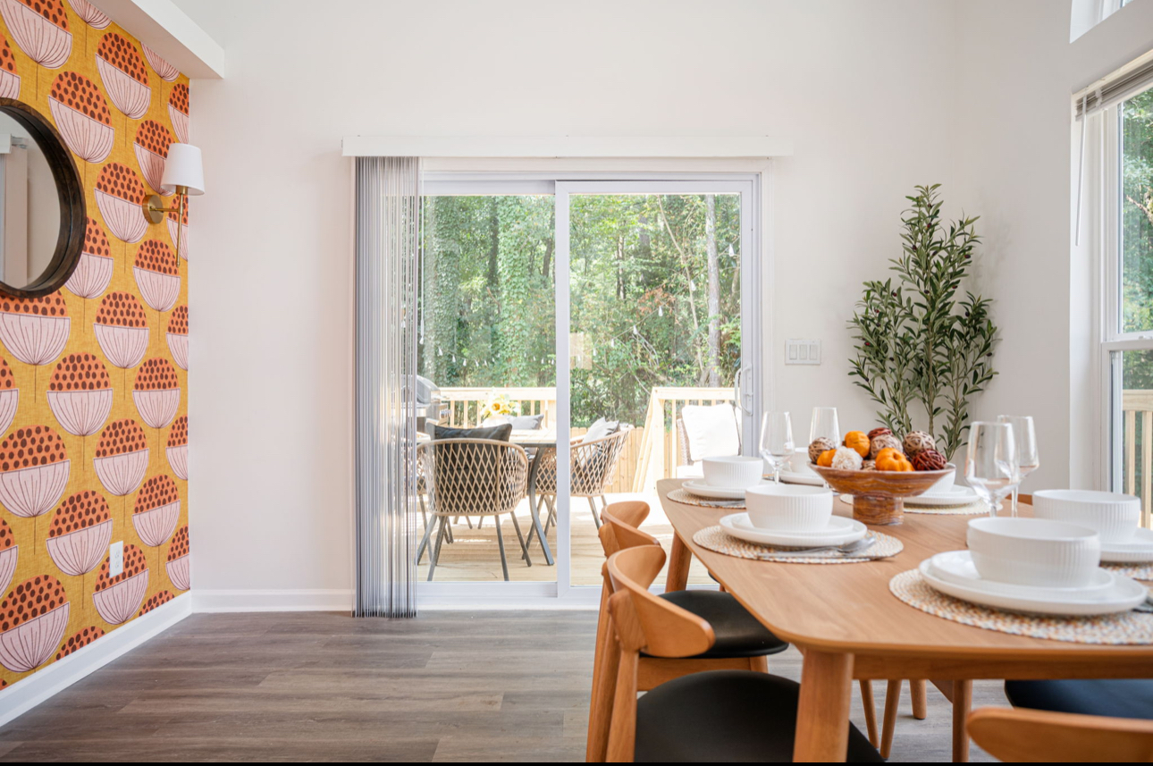 Dining room with orange patterned wallpaper, oak table set for six and deck views