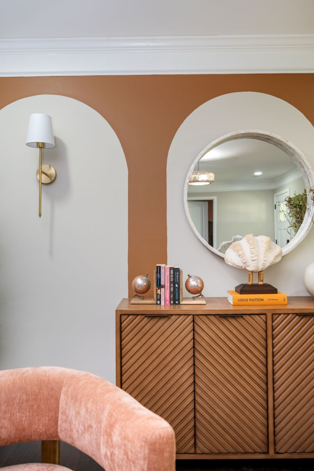 Custom painted terracotta arch wall with a round mirror and styled fluted console