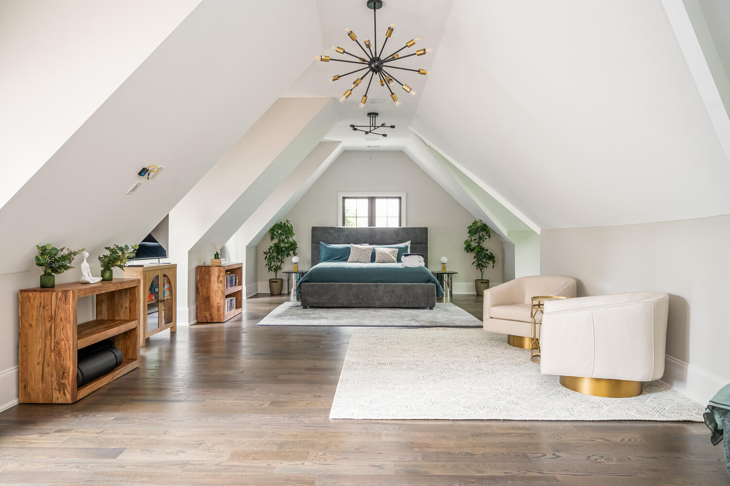 Vaulted attic primary suite with sputnik chandelier, teal bedding, and swivel chairs