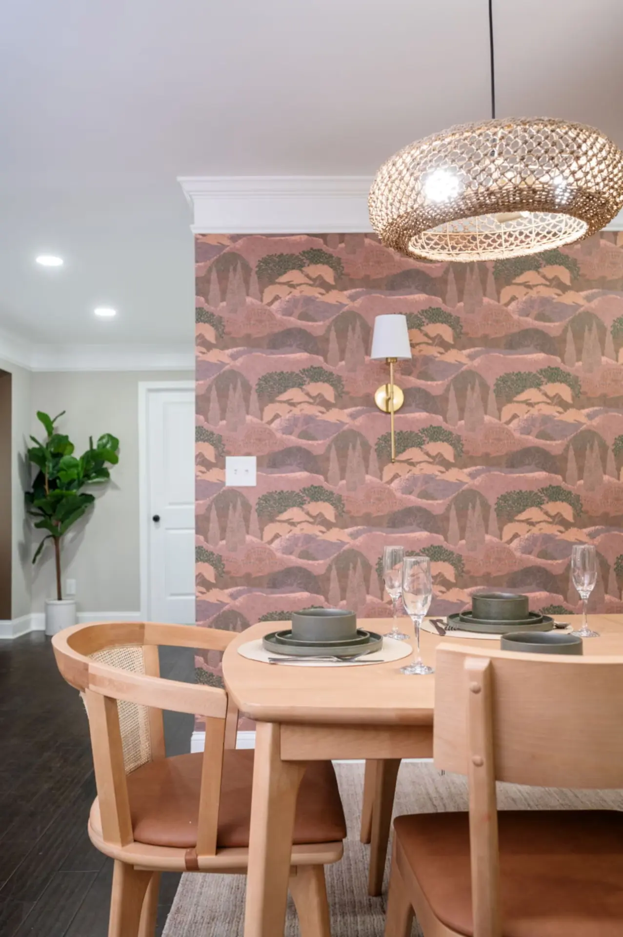 Dining room with landscape mural wallpaper, rattan pendant, and cane chairs